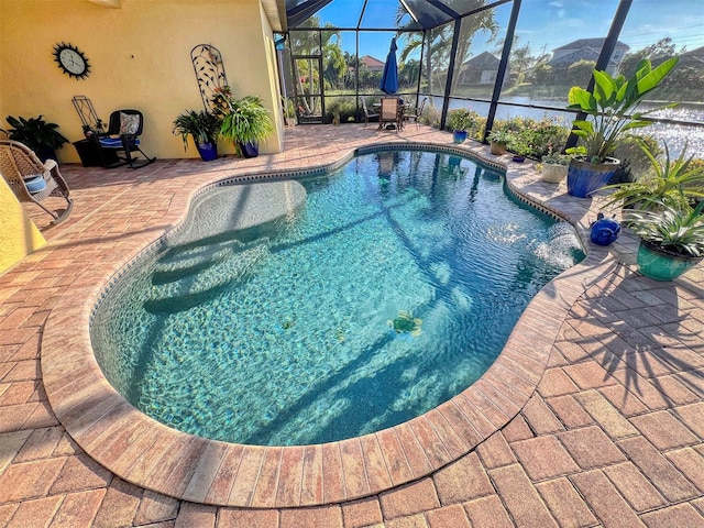 view of pool with glass enclosure, a water view, and a patio