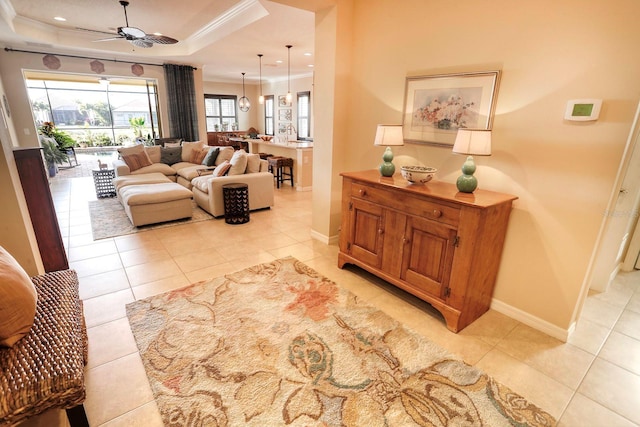 living room featuring ceiling fan, light tile patterned flooring, crown molding, and a tray ceiling