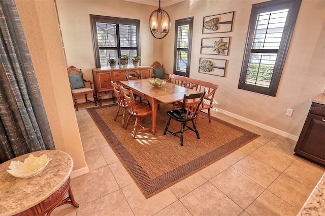 dining space with light tile patterned floors, an inviting chandelier, plenty of natural light, and crown molding