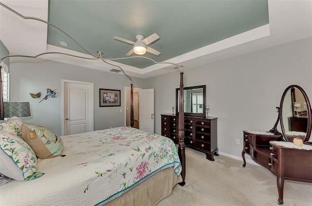 carpeted bedroom featuring ceiling fan and a tray ceiling