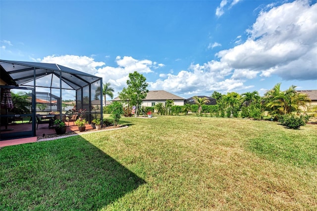 view of yard with glass enclosure and a patio