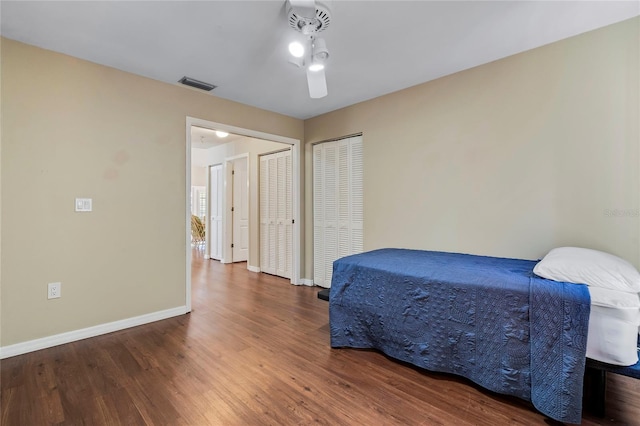 bedroom featuring dark hardwood / wood-style flooring, two closets, and ceiling fan