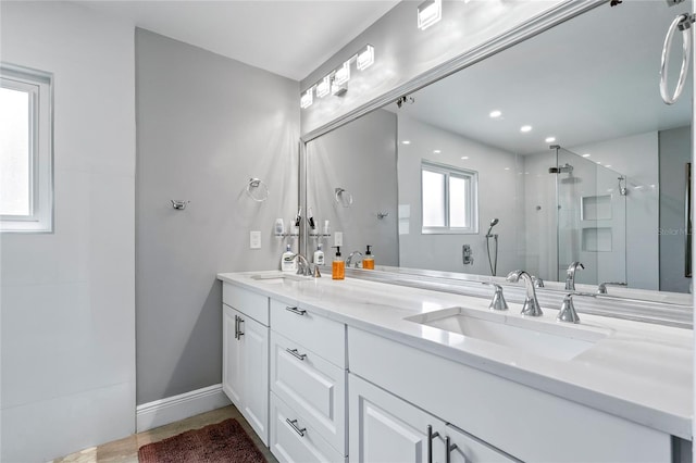 bathroom with vanity with extensive cabinet space, double sink, and an enclosed shower