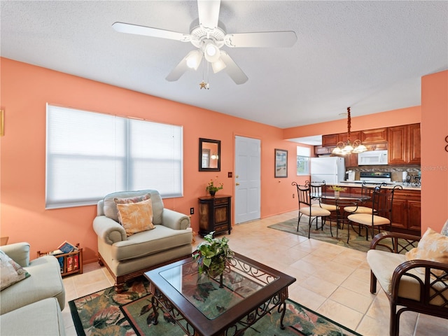 tiled living room featuring a textured ceiling, plenty of natural light, and ceiling fan with notable chandelier