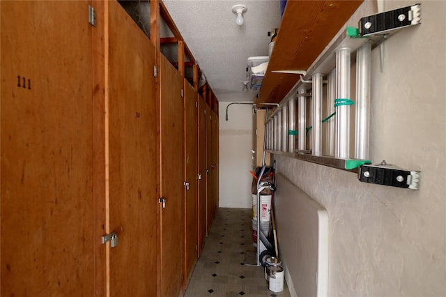 hall with a textured ceiling and light tile floors