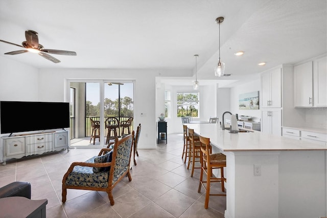 interior space featuring decorative light fixtures, ceiling fan, sink, light tile floors, and a breakfast bar