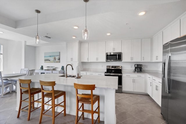 kitchen featuring a kitchen bar, an island with sink, white cabinets, light tile floors, and appliances with stainless steel finishes