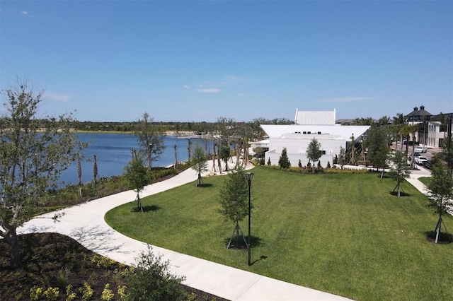 view of property's community with a water view and a lawn