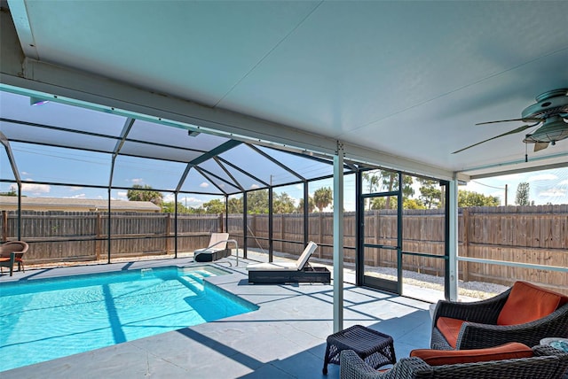 view of swimming pool with glass enclosure, ceiling fan, and a patio area