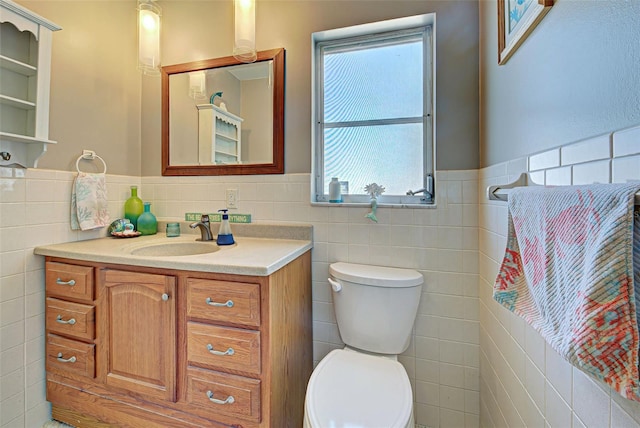 bathroom with vanity, toilet, and tile walls