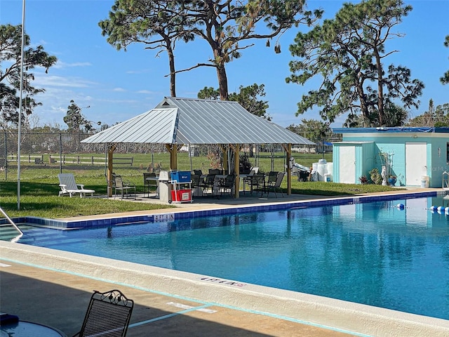 view of pool featuring a gazebo, a patio area, a lawn, and an outbuilding