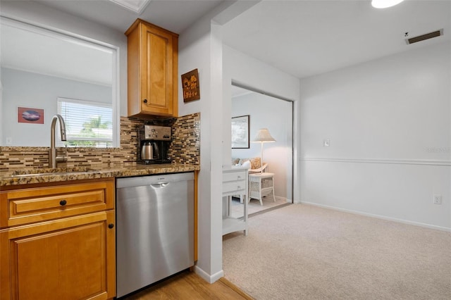 kitchen with stainless steel dishwasher, dark stone counters, sink, tasteful backsplash, and light colored carpet