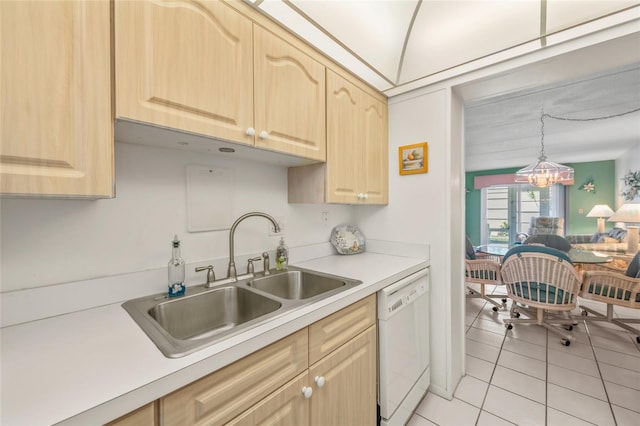 kitchen featuring white dishwasher, sink, light tile patterned floors, light brown cabinetry, and a chandelier