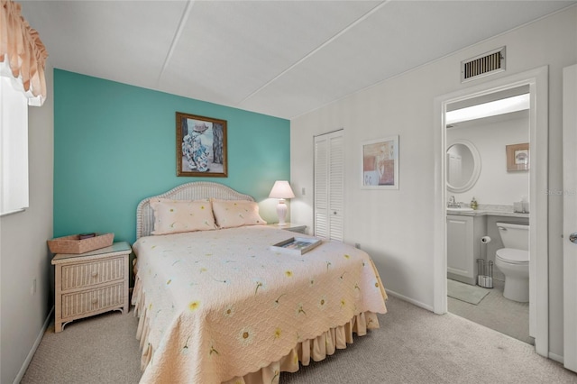 bedroom with light colored carpet, a closet, and ensuite bathroom