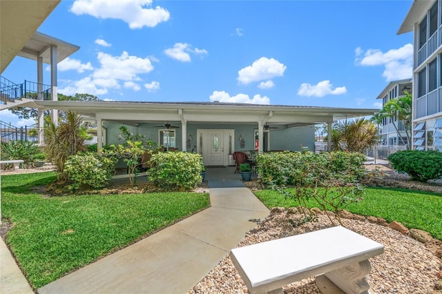 doorway to property with a lawn, ceiling fan, and a porch