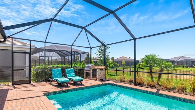 view of swimming pool featuring a grill, a patio, exterior kitchen, and a lanai