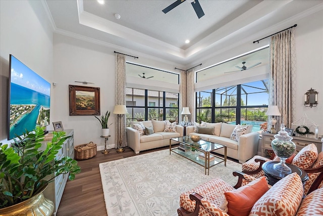 living room featuring crown molding, dark hardwood / wood-style floors, a raised ceiling, ceiling fan, and a high ceiling