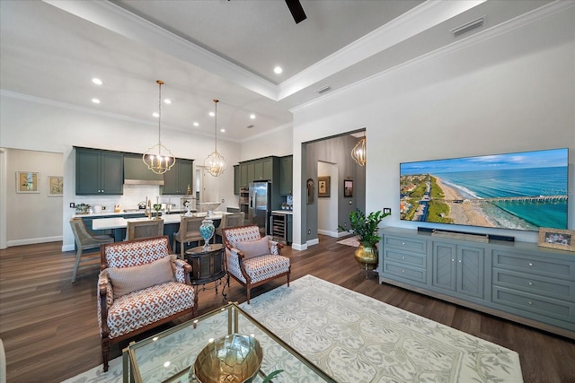 living room featuring sink, crown molding, dark hardwood / wood-style flooring, ceiling fan with notable chandelier, and beverage cooler