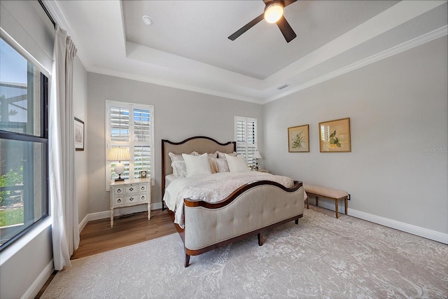 bedroom with crown molding, ceiling fan, a tray ceiling, and light hardwood / wood-style flooring