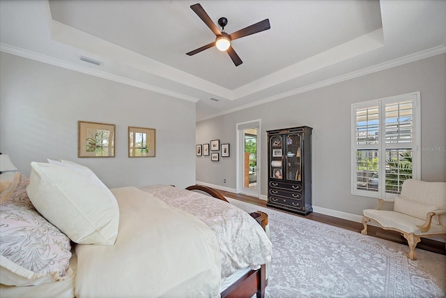 bedroom with hardwood / wood-style floors, ornamental molding, and a raised ceiling