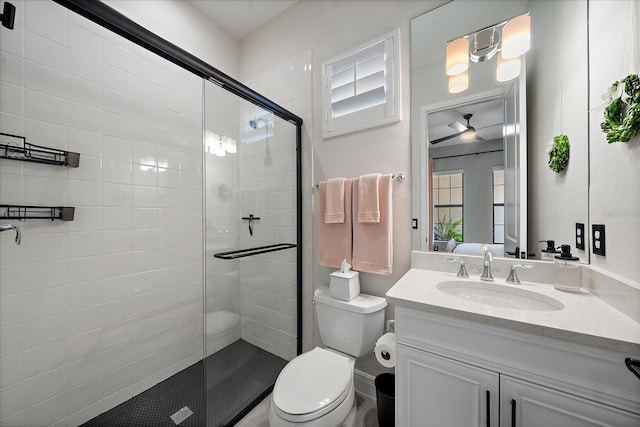 bathroom with toilet, vanity, ceiling fan, and a shower with shower door