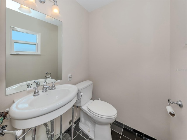 bathroom with toilet, tile patterned floors, and sink