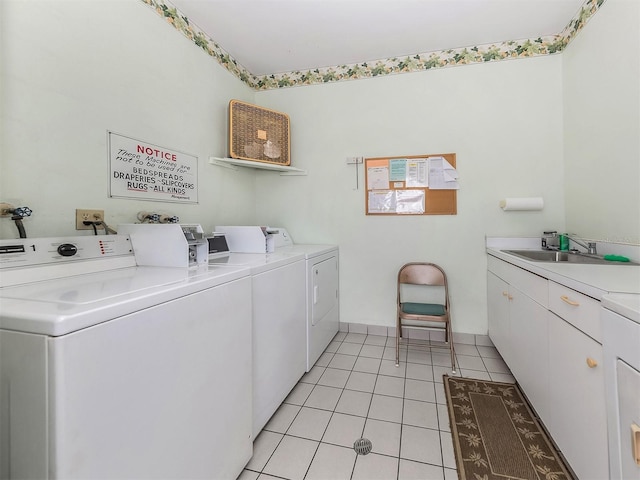 laundry room with washer and clothes dryer, light tile patterned flooring, cabinets, and sink