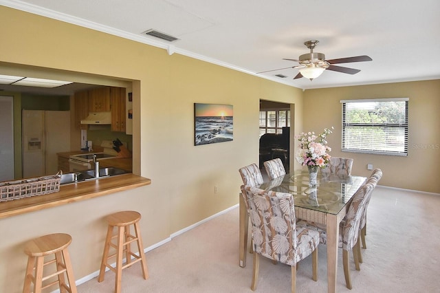 carpeted dining room featuring ceiling fan and ornamental molding