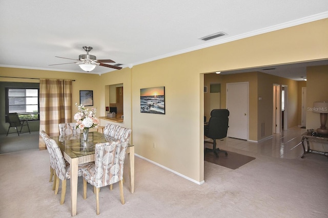 dining space with ceiling fan, light colored carpet, and ornamental molding