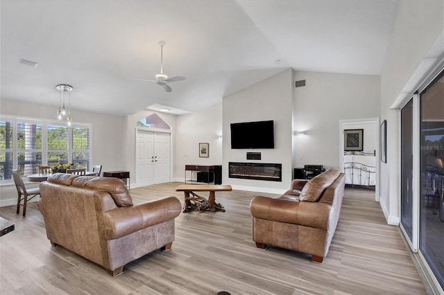 living room featuring ceiling fan, lofted ceiling, and light wood-type flooring