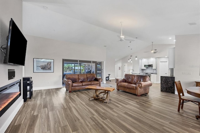 living room featuring sink, light hardwood / wood-style flooring, vaulted ceiling, and ceiling fan