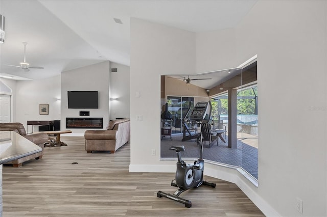 exercise area featuring light wood-type flooring, ceiling fan, and high vaulted ceiling