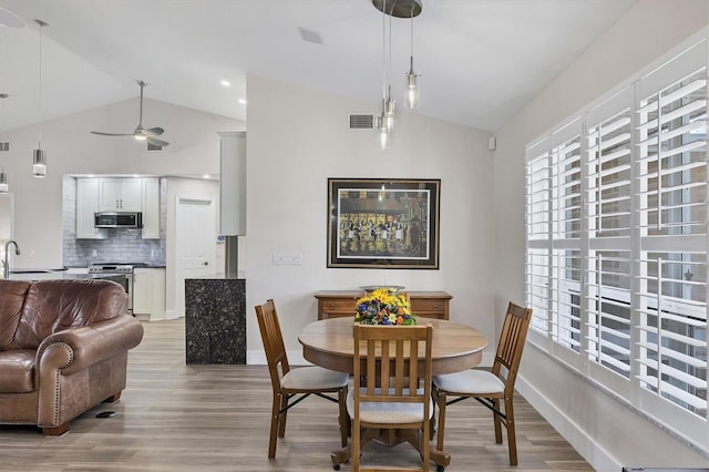 dining space featuring sink, ceiling fan, light hardwood / wood-style flooring, and lofted ceiling