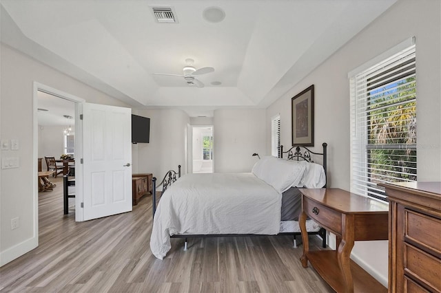 bedroom featuring ceiling fan, a raised ceiling, and light wood-type flooring