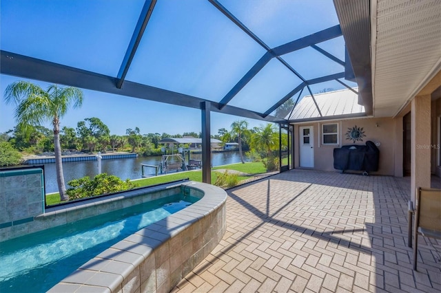 view of pool featuring glass enclosure, a patio, a water view, and area for grilling