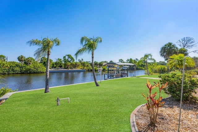 surrounding community with a dock, a water view, and a lawn