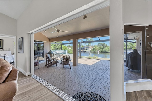 sunroom with ceiling fan, lofted ceiling, and a water view