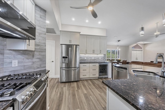 kitchen with hanging light fixtures, appliances with stainless steel finishes, sink, tasteful backsplash, and beverage cooler