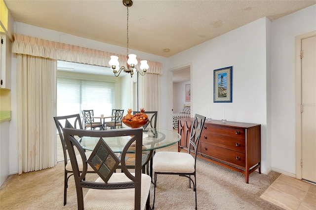 carpeted dining room featuring a notable chandelier and a textured ceiling