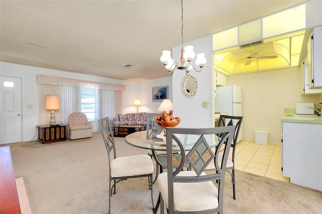 carpeted dining room with sink, a textured ceiling, and ceiling fan with notable chandelier