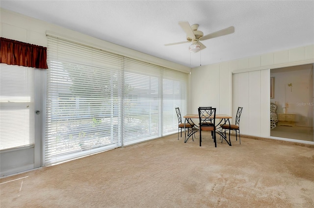 carpeted dining room featuring ceiling fan and a textured ceiling