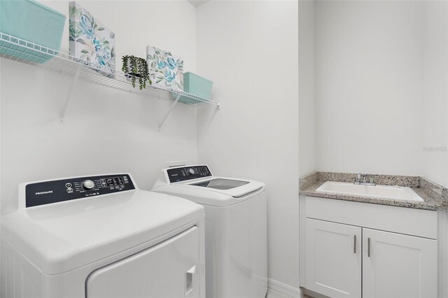 laundry area with washing machine and clothes dryer, cabinets, and sink