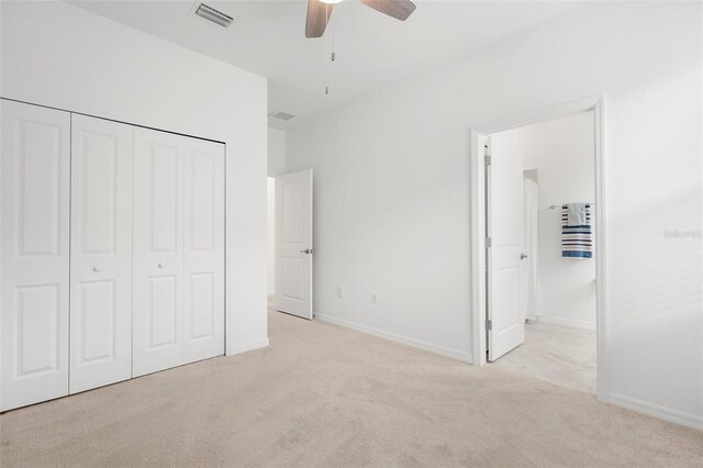 unfurnished bedroom featuring a closet, light colored carpet, and ceiling fan