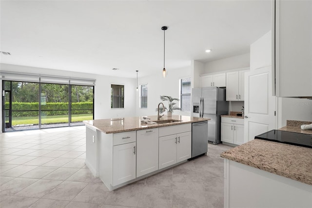 kitchen with white cabinetry, decorative light fixtures, stainless steel appliances, light stone countertops, and a center island with sink