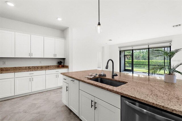 kitchen with stainless steel dishwasher, light stone counters, white cabinetry, and sink