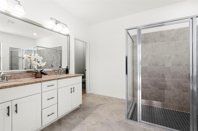 bathroom with vanity, toilet, and a shower with door