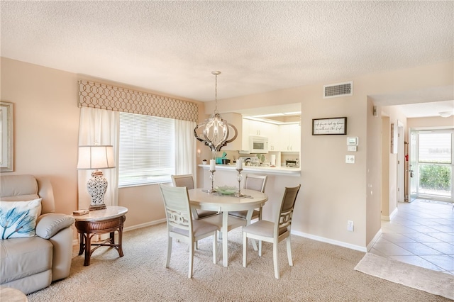 carpeted dining room with a chandelier and a textured ceiling