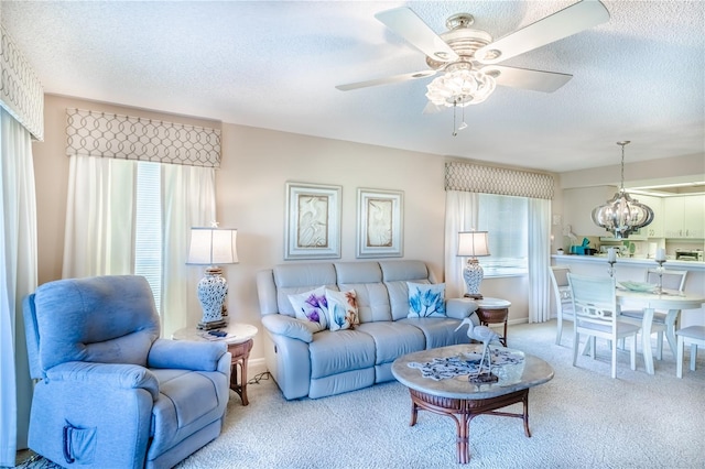 living room featuring carpet, ceiling fan with notable chandelier, and a textured ceiling