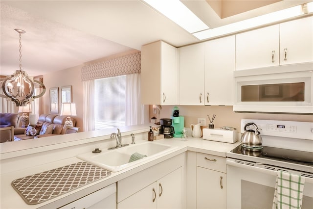 kitchen featuring white appliances, sink, an inviting chandelier, white cabinetry, and hanging light fixtures