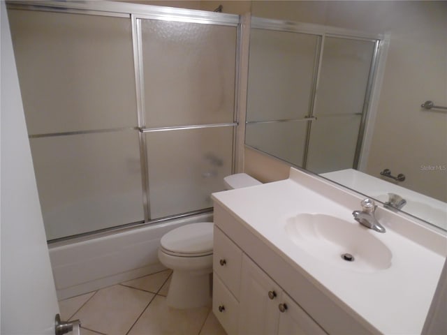 full bathroom featuring tile patterned flooring, vanity, toilet, and bath / shower combo with glass door